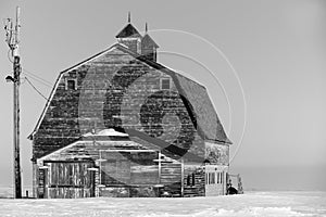 Black and white of an old, abandoned prairie barn surrounded by snow in Saskatchewan