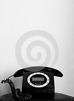 Black and white old/vintage looking telephone on black table with enough space to write