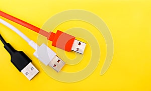 Black white and orange usb cables on yellow background