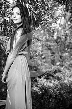 Black-white outdoor portrait of beautiful emotional young brunette woman in stylish dress