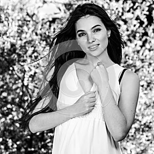 Black-white outdoor portrait of beautiful emotional young brunette woman in stylish dress
