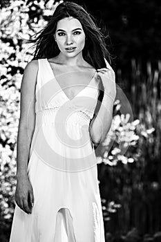 Black-white outdoor portrait of beautiful emotional young brunette woman in stylish dress