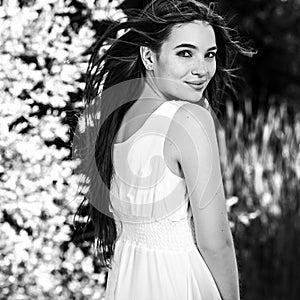 Black-white outdoor portrait of beautiful emotional young brunette woman in stylish dress