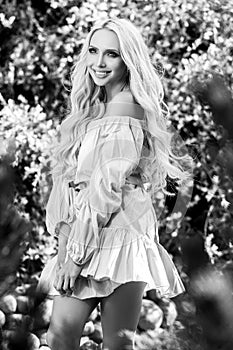Black-white outdoor portrait of beautiful young blond woman in stylish dress