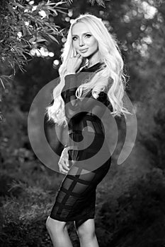 Black-white outdoor portrait of beautiful young blond woman in stylish dress