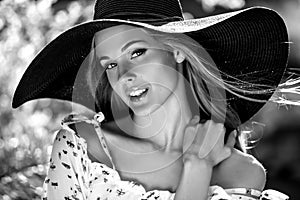 Black-white outdoor portrait of beautiful young blonde woman in black classic hat