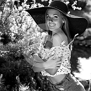 Black-white outdoor portrait of beautiful young blonde woman in black classic hat