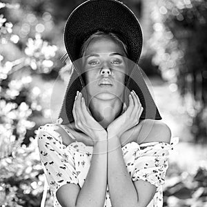 Black-white outdoor portrait of beautiful young blonde woman in black classic hat