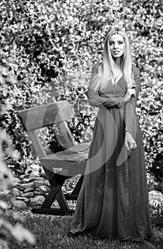 Black-white outdoor portrait of beautiful young smiling blond woman in stylish long dress