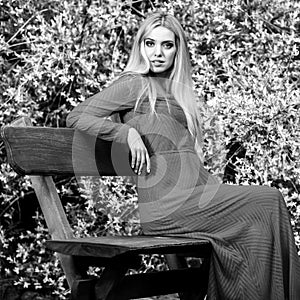 Black-white outdoor portrait of beautiful young smiling blond woman in stylish long dress