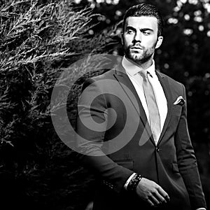 Black-white outdoor portrait of elegant handsome man in classical suit