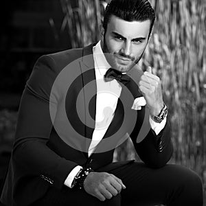 Black-white outdoor portrait of elegant handsome man in classical suit