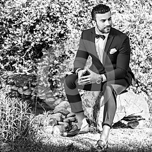 Black-white outdoor portrait of elegant handsome man in classical suit