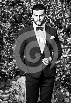 Black-white outdoor portrait of elegant handsome man in classical suit