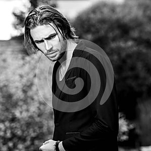 Black-white outdoor portrait of elegant long hair handsome man