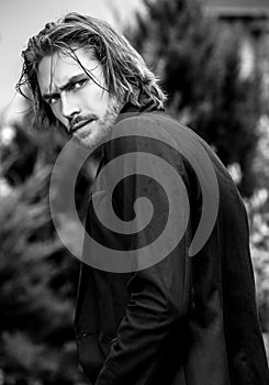 Black-white outdoor portrait of elegant long hair handsome man