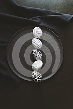 Black and white painted easter eggs lined up in a row on black background, top view shot