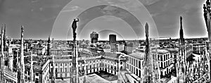 Black and white panorama photo of marble statues of Cathedral Duomo di Milano on piazza,Milan cityscape and Royal Palace of Milan