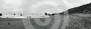 Black and white panoramic image of a rocky beach on the california coast