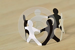 Black and white paper people in a circle holding hands - Anti-racism concept