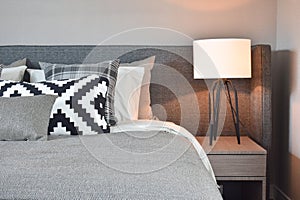 Black and white pattern pillows with gray blanket and white table lamp