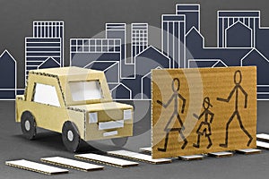 Black and white pedestrian crossing with cardboard stopped car and pedestrians cross the road safely