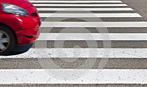 Black and white pedestrian crossing with red car on background - image with copy space - The car`s shape has been modified and is