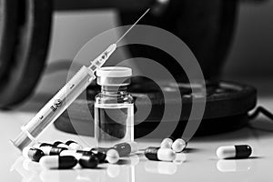 Black and white pharmaceutical syringe with needle and medical pills - illegal doping drugs in sport