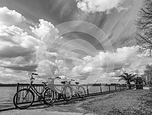 Black and white photo of 3 parked bicycles and a cloudy sky