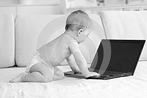 Black and white photo of adorable baby boy whith laptop