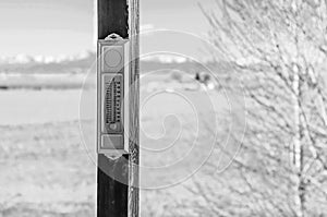 Black and white photo of an analog thermometer mounted outside