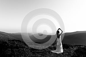 Black and white photo, a beautiful bride in a white wedding dress silhouetted from the rays of the sun
