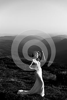 Black and white photo, a beautiful bride in a white wedding dress silhouetted from the rays of the sun