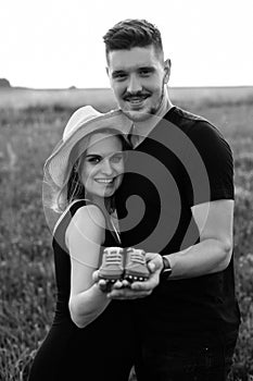 Black and white photo of beautiful young pregnant couple happy waiting for baby and holding baby shoes. Carefree and happy.