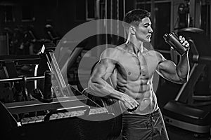 A black-and-white photo of a bodybuilder athlete, holds a black