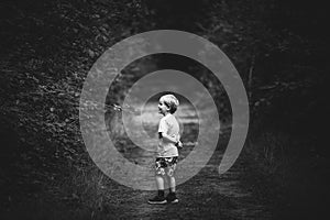 Black and white photo of a boy walking in a park