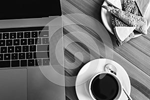 Black and white photo. Break concept. Flat lay view of a workspace with a laptop on a wooden table, with a cup of coffee. Copy