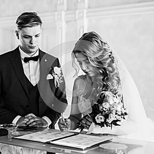 Black and white photo. the bride and groom signing the marriage contract.