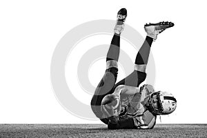 Black and white photo. Catching ball and falling. Man, professional american football player over white studio