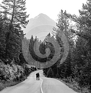 couple together in middle of road in front of mountain background