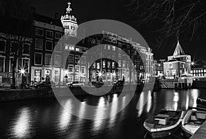 Black-white photo of cruise boat moving on night canals of Amsterdam in Amsterdam, Netherlands.