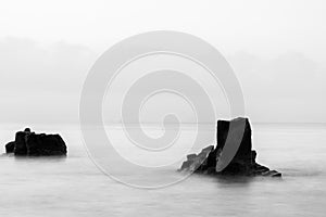 Black and white photo exposes the sea surface with ancient lava rocks protruding above