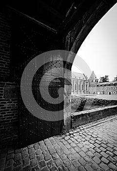 Black and white photo of a gate leading towards a building