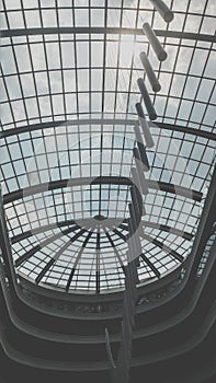 Black and white image of glass roof dome and light hanging on ceiling at modern office building