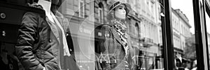 Black and white photo of glass storefronts with manikins, manikins in sold clothes