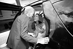 Black-and-white photo .happy couple talking near wedding limo