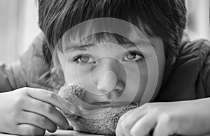 Black and white photo of Kid with bored face,Lonely boy putting his chin down on teddy bear and looking out, Upset preschool child