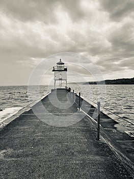 black and white photo of a lighthouse with a pier on the edge