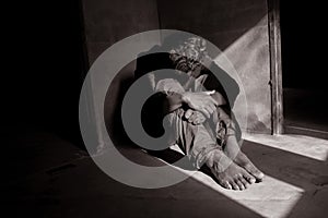 Black and white photo. Lonely man sitting on the floor. He is unhappy and sad