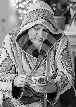 Black and white photo of a man in a robe drinking tea after a bath, portrait of a man